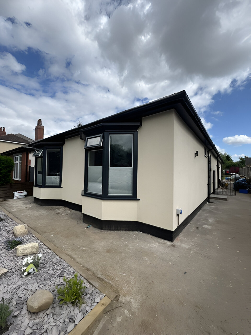 Cream bungalow with dark sprayed window frames and roofline